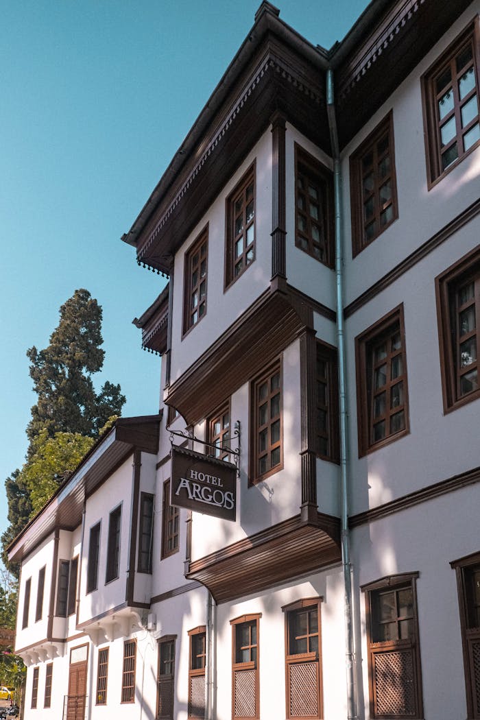A view of a charming old-fashioned hotel's wooden facade with a classic sign and multiple windows.
